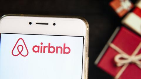 Airbnb app on a phone against a background of wrapped gifts