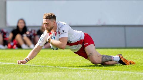 Ethan Ryan with the ball under one arm diving to score a try