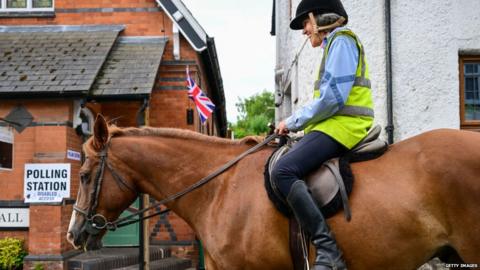 Woman passes polling station on horseback in Uffculme, Devon