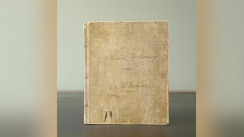 An image of a dictionary from the 19th century which is light brown in colour