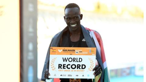 Kibiwott Kandie holding a banner with 'world record' on it