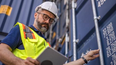 Man working on building site looking at tablet device