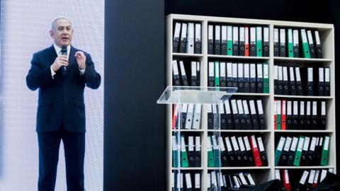 Israeli PM Benjamin Netanyahu stands on stage presenting what he says are documents seized from Iran's nuclear archive