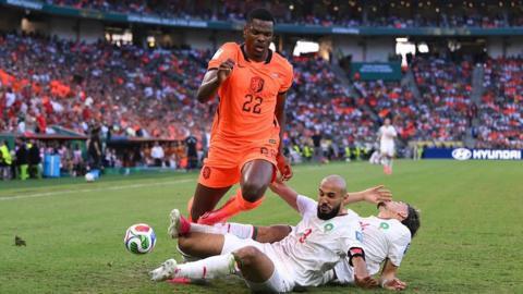 Denzel Dumfries is challenged by two Morocco defenders