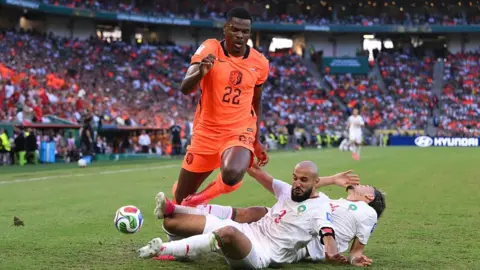 Denzel Dumfries is challenged by two Morocco defenders
