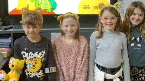 Children from Bransgore C of E Primary School smiling at the camera with Pudsey style yellow ears on their heads