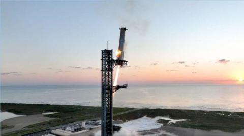 SpaceX booster about to be caught by a huge pair of mechanical arms.