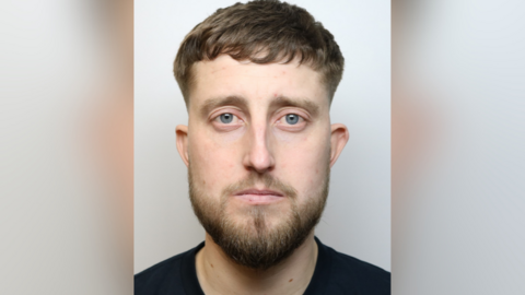 James Farmer's custody mugshot, he is seen wearing a black shirt. He has a beard and short hair.