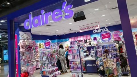 A Claire's store in Paris, with it's purple logo, and array of colourful items inside the store on racks.