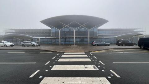 The front of a small airport on a foggy day.
