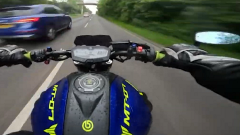 A still from the video posted by Benjamin Males shows the blue and yellow bike overtaking other cars at high speeds on local roads. The nandlebars and mirror are visible.
