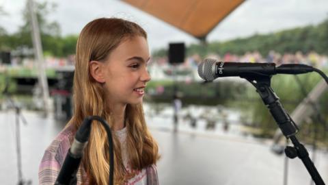 Side angle of Anna on a stage with a microphone