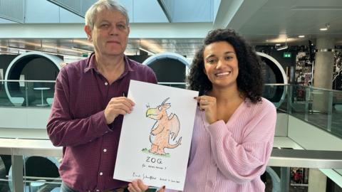 Axel Scheffler stands with Nina holding a hand drawn picture of Zog