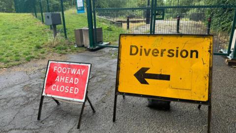 Two signs reading 'Footway ahead closed' and 'Diversion' in front of a green gate