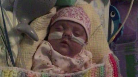 Arwen mewn cryd ysbyty dan flanced liwgar a gyda thiwbiau yn ei thrwyn yn fuan wedi ei genedi gaeth