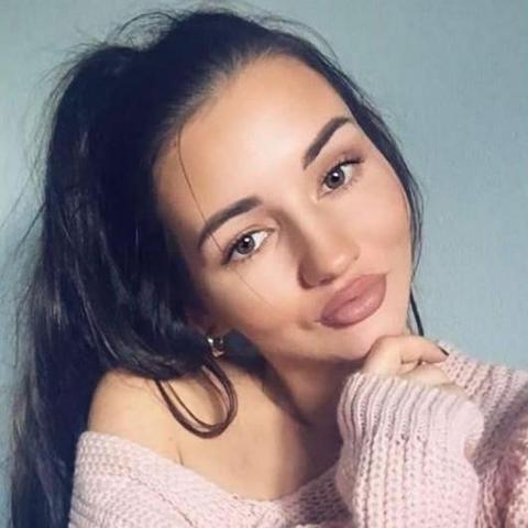 A head and shoulders image of a woman with long black hair and a pink top.