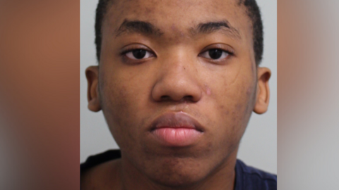 Sakhile Ntsele police mugshot. A young man with a dark blue top stares straight at the camera.