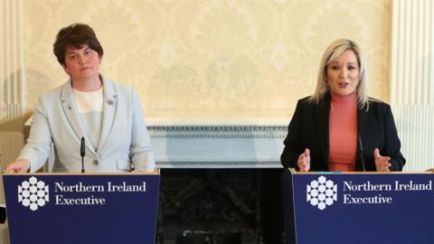 Two women standing behind blue lecterns