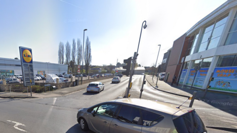 The entrance to a T junction with a crossing and traffic lights, with a Lidl supermarket nearby