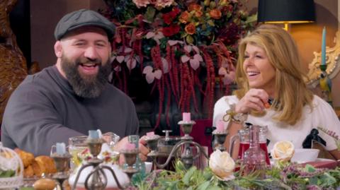 Joe and Kate laugh as they speak at the breakfast table