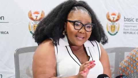 Education Minister Siviwe Gwarube is seen in a white top as she speaks at an official event