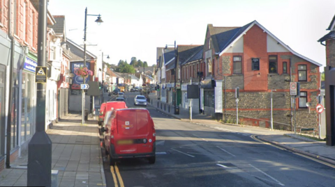 Street view of Blackwood high street, two red royal mail vans are parked on the left hand side of the road. 