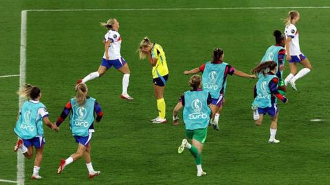 Smilla Holmberg of Sweden looks dejected as England players celebrate following the team's victory in the penalty shoot out at Euro 2025