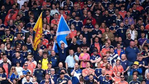 A crowd of football fans wearing Scotland tops in a stadium