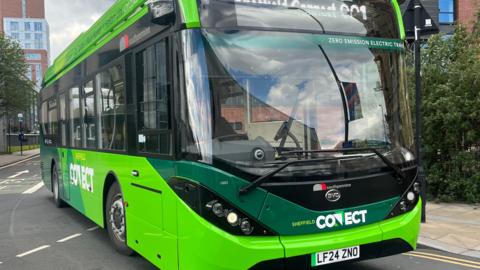 A green Sheffield Connect electric bus in Sheffield's city centre.