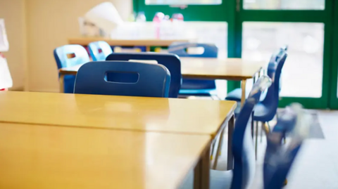 A general view picture of plastic chairs and desks in a classroom.