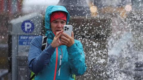 A person takes pictures with their phone at the esplanade