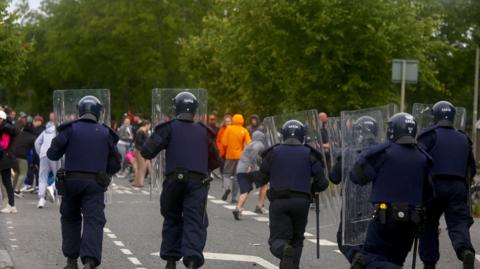 The Garda Public Order Unit stand in front of protestors near the site of a former factory in Coolock, Dublin, Ireland