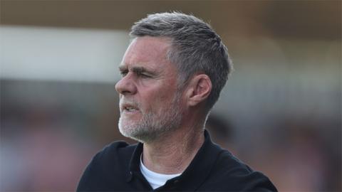 Bradford City manager Graham Alexander looks out with a frustrated and perplexed facial expression.