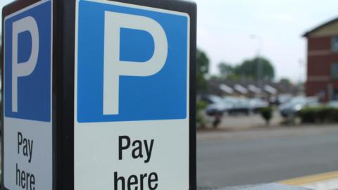 A parking sign - a black board with a blue P in a white background. 