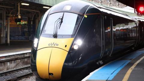 A Great Western Railway train pulling into a train station platform.