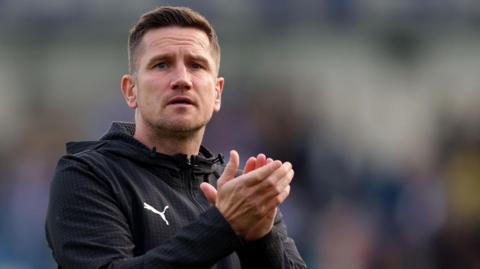 Crewe boss Lee Bell applauds the crowd after a game