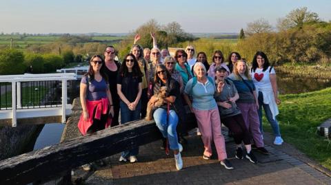 A group of women standing next to a lock, near a canal
