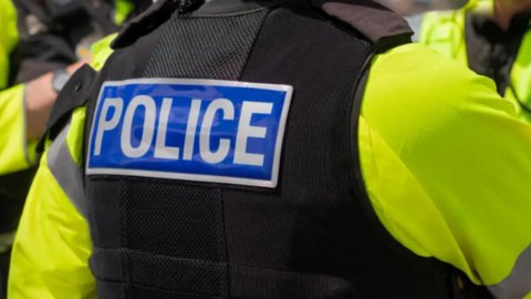Police officers in flak jackets and yellow bibs