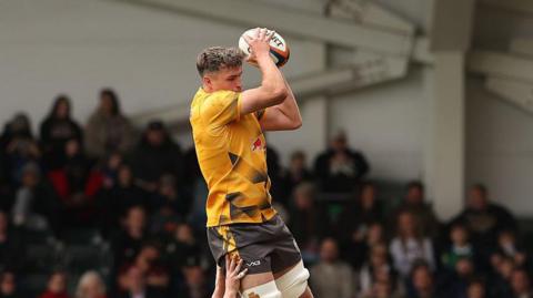 Adam Scott, wearing Newcastle Red Bulls' yellow away kit, catches the ball at a line-out