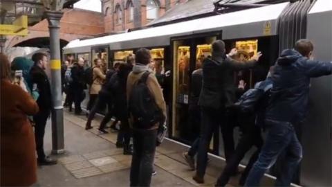 Passengers push doors shut on tram