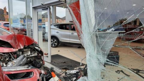 Damaged car after crashing into glass showroom building