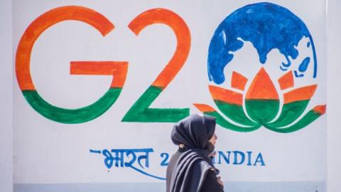 A Kashmiri woman walks in front of a sign ahead of the G20 summit on May 21, 2023 in Srinagar, Indian administered Kashmir, India. The Group of Twenty (G20) is the premier forum for economic cooperation worldwide.