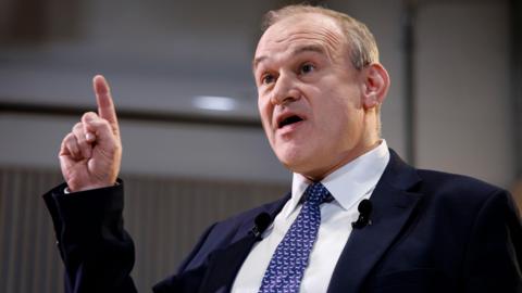 Liberal Democrats Party leader Sir Ed Davey points to the sky as he delivers a speech regarding British leadership on trade and defence.