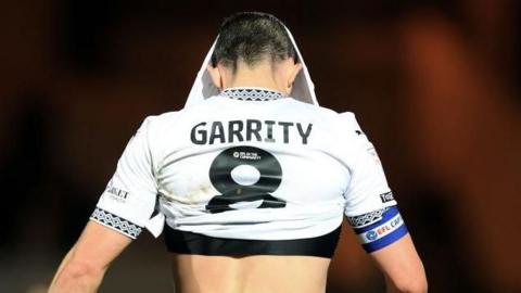 Port Vale's Ben Garrity walks away with his shirt pulled over his head in disappointment