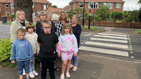 A group of women and children standing on the pavement close to a zebra crossing on Beckfield Lane, Acomb, York