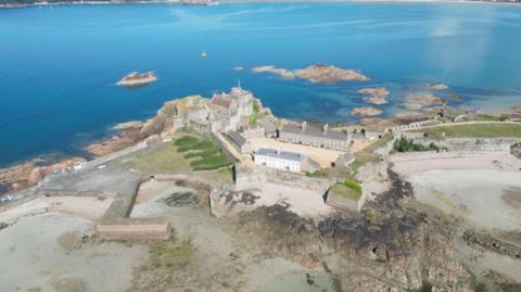 An aerial photograph of Elizabeth Castle in Jersey. It is on an island and surrounded by the sea.