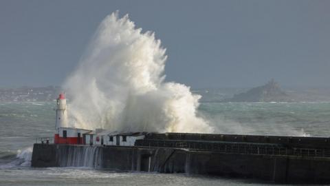 A large wave hits a lighthouse