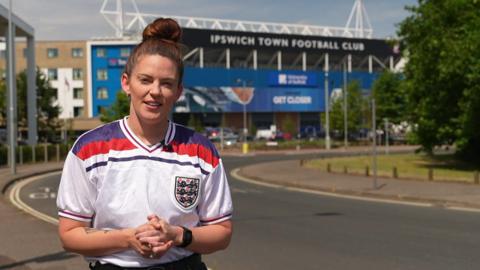 Zoie O'Brien wearing an England shirt, outside Ipswich Town Football Club's stadium