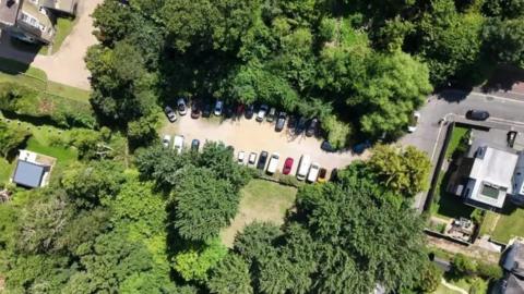 A drone shot of Mornington Road car park, a small paved area encircled by trees.