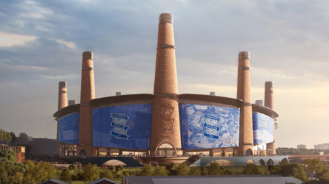 The stadium is circular with large chimneys at several points around it. In between is blue with club insignia on it. Some trees/greenery can be seen in the foreground at ground level.